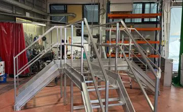 Scala in acciaio inox con passerella per scavalcare un macchinario industriale